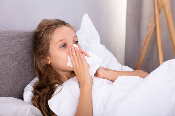 Girl Suffering From Cold Blowing Her Nose With Handkerchief On Bed - Фото, изображение