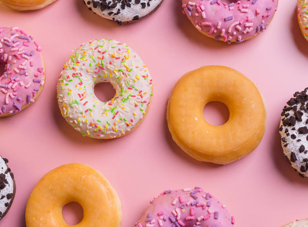Top view of many colorful donuts on pink background. - Фото, зображення