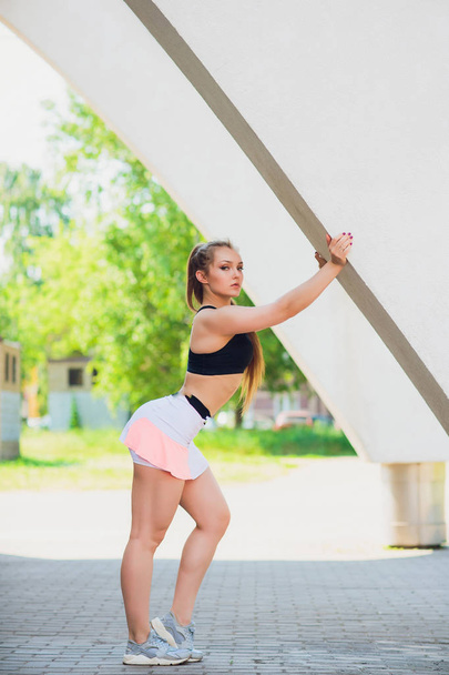 Fitness sportieve meisje dragen van mode kleding over straat muur, buitensport, stedelijke stijl. Tiener model in swag kleren poseren buiten - Foto, afbeelding