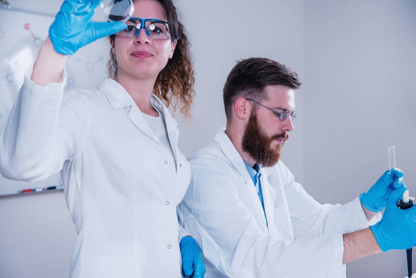 Νέος επιστήμονας κάνει πειράματα στο εργαστήριο, φορώντας εξοπλισμός ασφαλείας - Φωτογραφία, εικόνα