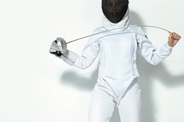 Young fencer athlete wearing fencing costume and mask holding the sword. Isolated on white background - Fotoğraf, Görsel