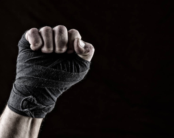 lifted up fist of athlete wrapped in black textile bandage, gesture of solidarity - Photo, Image