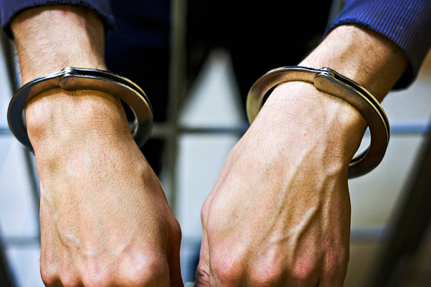 Mãos masculinas em algemas de metal close-up. Um prisioneiro na prisão. o conceito de punição por um crime
 - Foto, Imagem