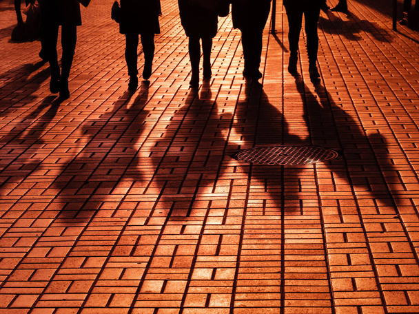 Έννοια του life style. Φως και σκιές στην πόλη. Σιλουέτες ανθρώπων περπατώντας στους δρόμους της μεγαλούπολης και να φωτίζονται από πίσω φως. Σκιές των ανθρώπων το περπάτημα street στο φως του δειλινού. - Φωτογραφία, εικόνα