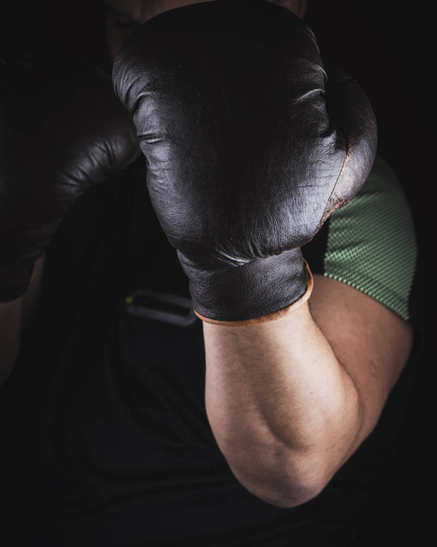 Sportler steht in einem Boxregal und trägt braune Lederhandschuhe - Foto, Bild
