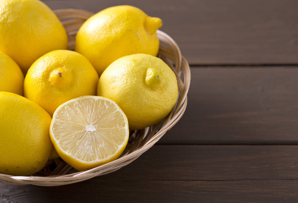 lemons in basket on brown wooden surface - Φωτογραφία, εικόνα