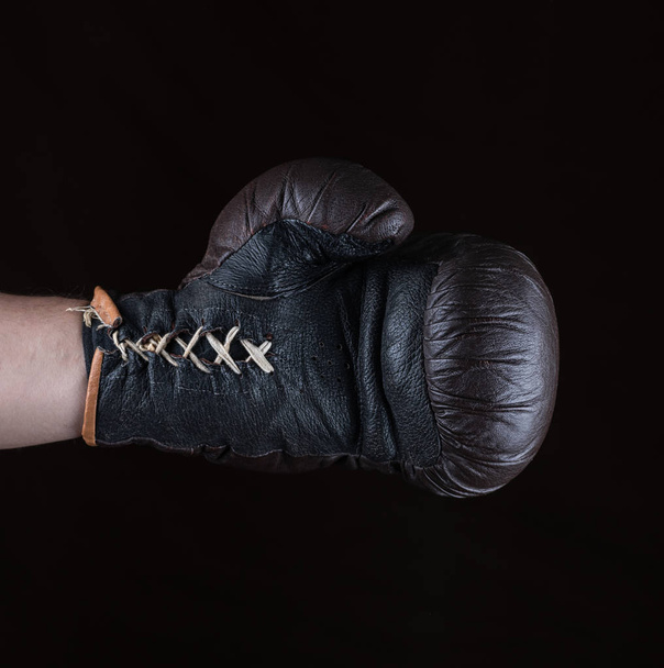 guante de boxeo marrón vestido en la mano del hombre, fondo negro
 - Foto, Imagen