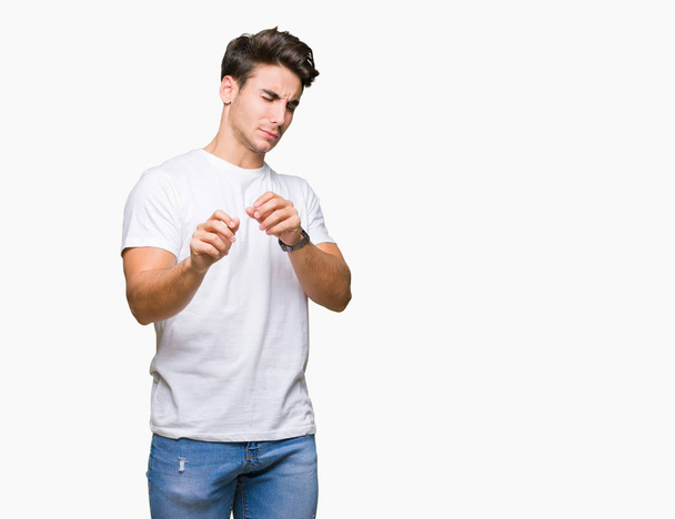 Young handsome man wearing white t-shirt over isolated background disgusted expression, displeased and fearful doing disgust face because aversion reaction. With hands raised. Annoying concept. - Zdjęcie, obraz