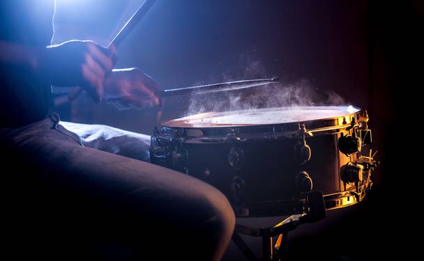 man speelt de snaredrum op een mooie gekleurde achtergrond, het concept van muziekinstrumenten - Foto, afbeelding