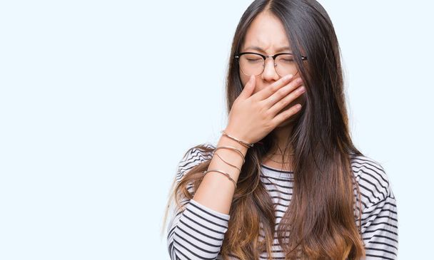 Young asian woman wearing glasses over isolated background bored yawning tired covering mouth with hand. Restless and sleepiness. - Foto, Imagen