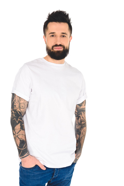 bel homme barbu avec des tatouages et les mains dans les poches regardant la caméra isolée sur blanc
 - Photo, image