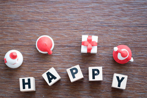 glückliches Wort hölzerner Buchstabenblock glücklich mit Spielzeug der Weihnachtsdekoration auf Holzgrund - Foto, Bild
