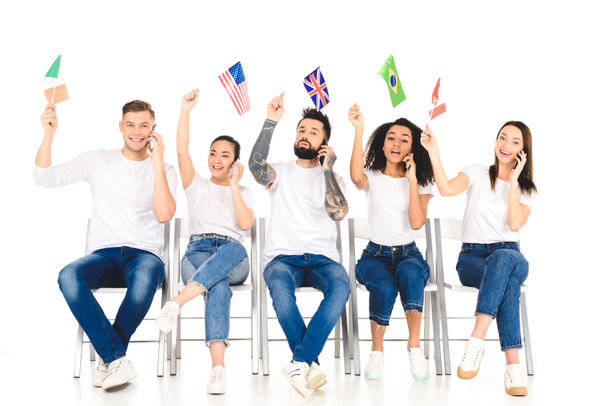 багатоетнічна група молодих людей розмовляє по смартфонах і тримає прапори над головами ізольовані на білому
 - Фото, зображення