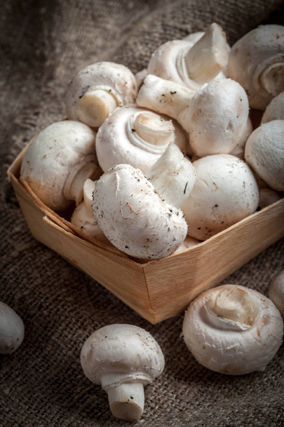 Harvest of white mushrooms on jute and wooden texture. Selective focus. - Foto, immagini