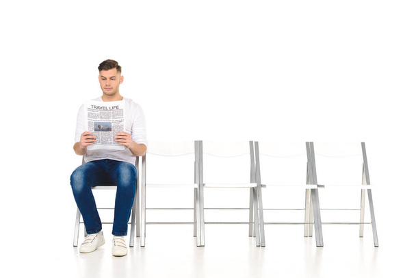 schöner, einsamer junger Mann liest Zeitung isoliert auf weiß - Foto, Bild