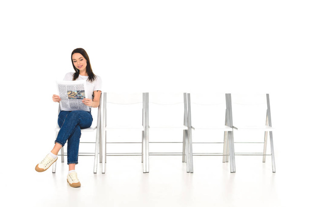 houkutteleva tyttö istuu tuolilla ristissä jalat ja lukeminen sanomalehti eristetty valkoinen
 - Valokuva, kuva