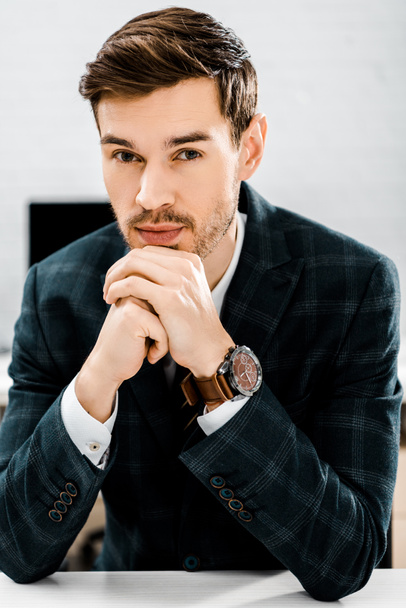 portrait of thoughtful businessman in suit looking at camera in office - Foto, imagen