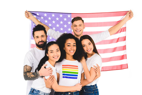 gruppo multietnico di giovani che sorridono e si abbracciano mentre tengono la bandiera degli Stati Uniti isolata sul bianco
 - Foto, immagini