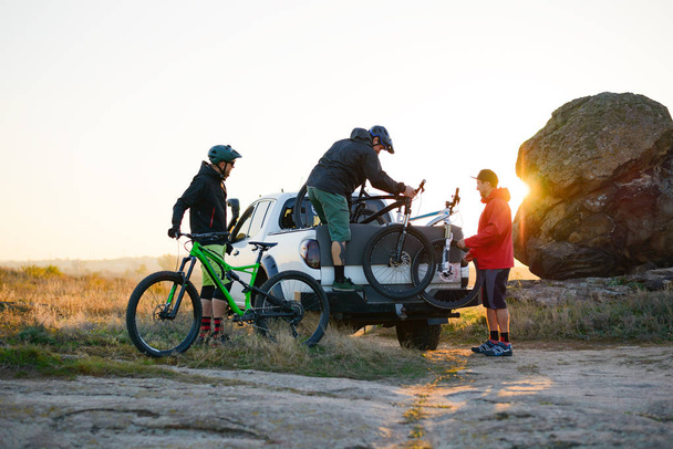 Friends Taking MTB Bikes off the Pickup Offroad Truck in Mountains at Sunset. Adventure and Travel Concept. - Foto, Bild