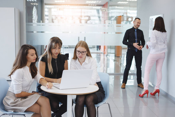 オフィスのスタッフのチーム。ビジネスの女性と男座ってノート パソコンをテーブルの横に立つし、将来の法人のコンセプトを計画します。チームワーク。男女共同参画. - 写真・画像