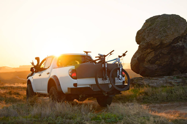 Friends Driving Pickup Offroad Truck in the Mountains with Bikes in the Body at Sunset. Adventure and Travel Concept. - Photo, Image