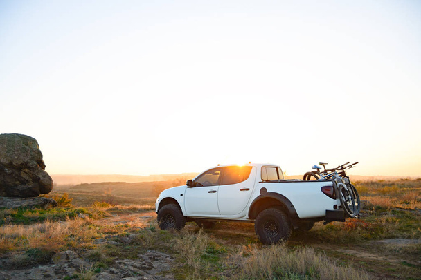 Pickup Offroad Truck with Bikes in the Body in the Mountains at Sunset. Adventure and Car Travel Concept. - Foto, imagen
