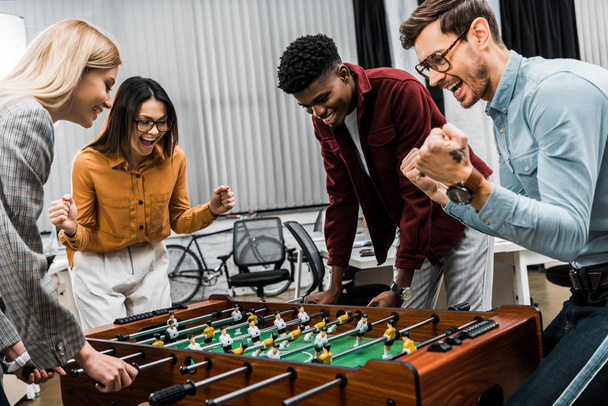 multicultural business colleagues playing table football together in office - Фото, изображение