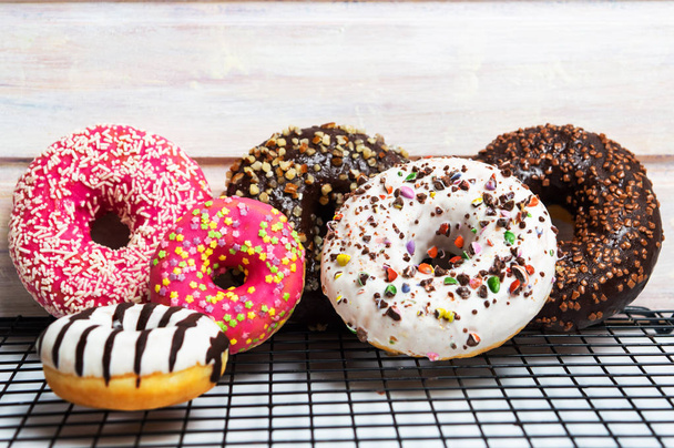 Donuts de chocolate decorados em uma grade de cozimento vista superior
 - Foto, Imagem