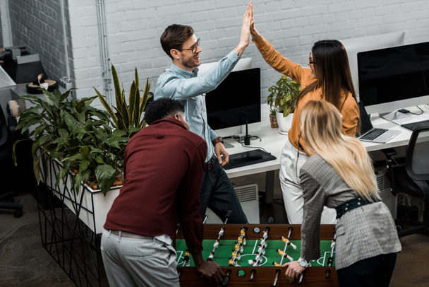 multicultural business colleagues playing table football together in office - Фото, изображение