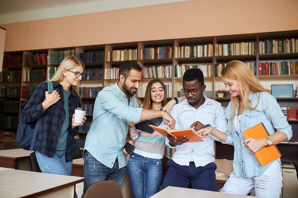 Studenti multirazziali si divertono in biblioteca mentre si preparano per gli esami
. - Foto, immagini