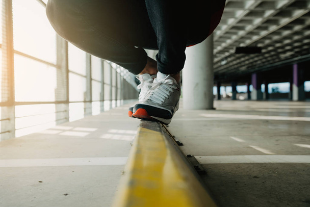 建物内のレールの上を歩くスニーカーの男性の足のクローズ アップ - 写真・画像