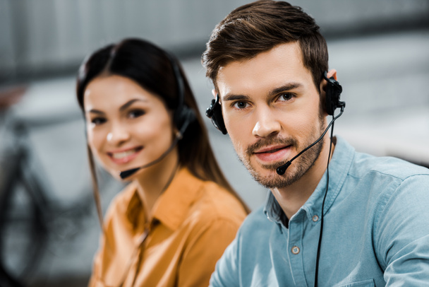 smiling call center operators in headsets looking at camera in office - Foto, Bild