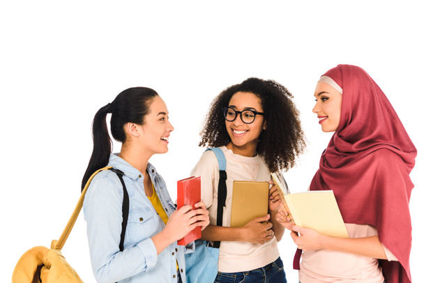 allegre ragazze multiculturali in piedi e ridendo con libri isolati su bianco
  - Foto, immagini