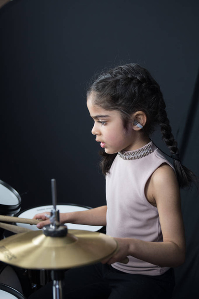 イギリスのインド人 - ドラムの練習や読書音楽ノート - 暗い黒の背景上の 5 歳の少女. - 写真・画像