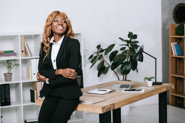 beautiful african american businesswoman with crossed arms in modern office  - Zdjęcie, obraz