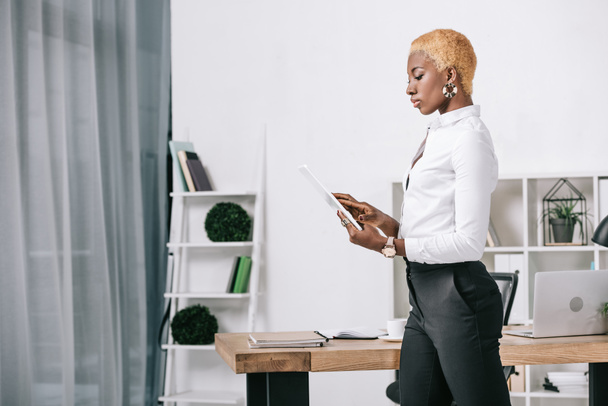  african american businesswoman with short hair using digital tablet near table in office - Φωτογραφία, εικόνα