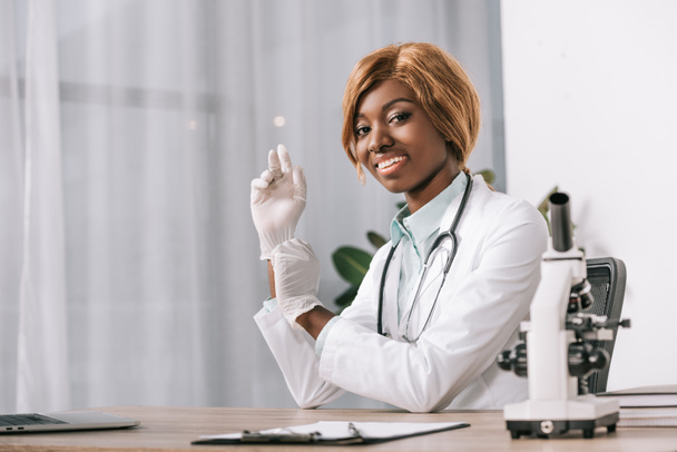 cheerful female african american scientist  wearing latex gloves - Fotografie, Obrázek