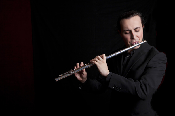 professional flutist musician playing flute on black background - Foto, imagen