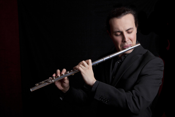 professional flutist musician playing flute on black background - Fotoğraf, Görsel