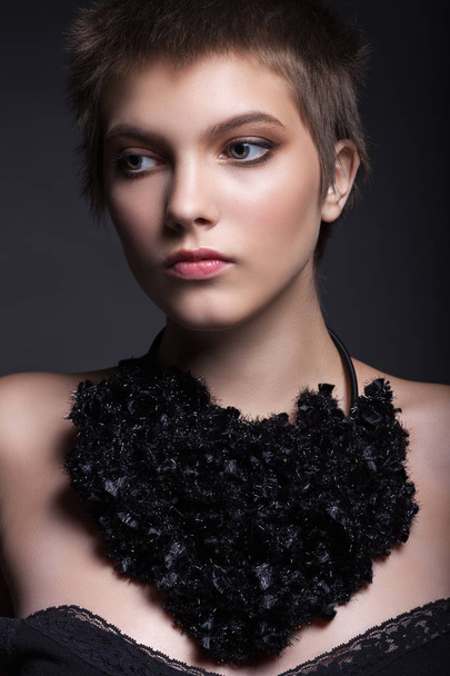 Portrait of a beautiful girl close-up. With a beautiful make-up and a necklace on a black background. - Photo, Image