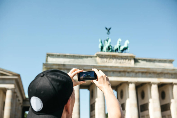 Τουριστικές φωτογραφίες σε ένα κινητό τηλέφωνο την πύλη του Βρανδεμβούργου στο Βερολίνο στη Γερμανία. - Φωτογραφία, εικόνα