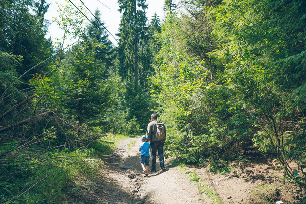 Pai com o filho a passar por um rasto florestal. conceito de caminhadas
 - Foto, Imagem