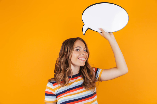 Image of happy young beautiful girl posing isolated over yellow background holding speech bubble. - Fotografie, Obrázek