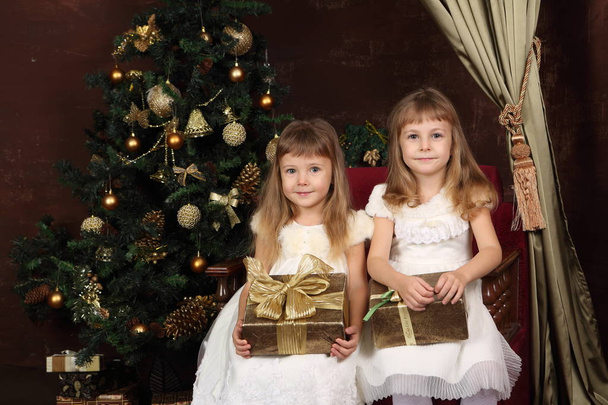 two little girls with gifts near the new year tree - Fotoğraf, Görsel