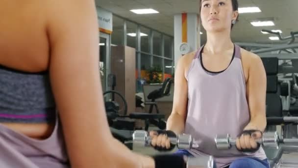 Training. A young woman pumps her hand muscles with a dumbbells. Looking in the mirror - Filmagem, Vídeo