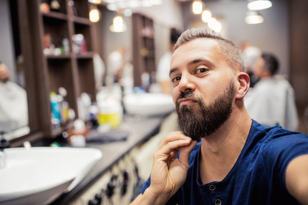 Hipster man client visiting haidresser and hairstylist in barber shop. - Foto, afbeelding