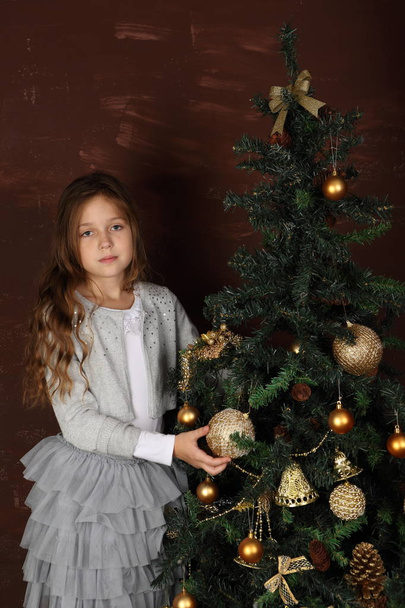A girl in a beautiful dress near the New Year tree - Zdjęcie, obraz