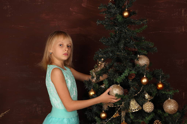 A girl in a beautiful dress near the New Year tree - Φωτογραφία, εικόνα