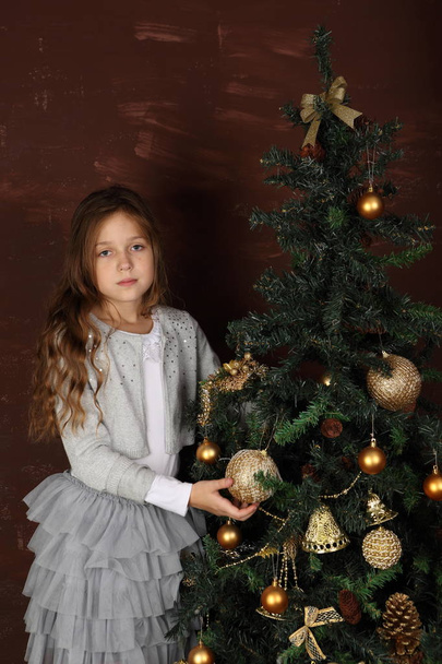 A girl in a beautiful dress near the New Year tree - Zdjęcie, obraz