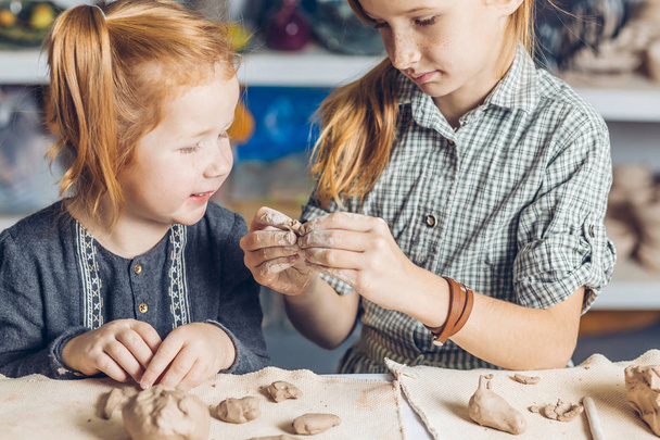 girl showing her little sister to create a clay toys - Fotografie, Obrázek